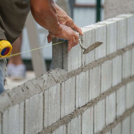 Albañil haciendo una pared con bloques y cemento
